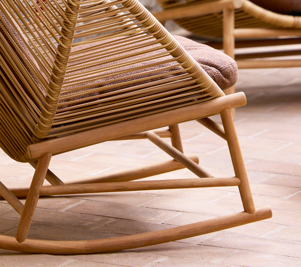 Eine Nahaufnahme eines Holz-Schaukelstuhlgestells mit einem geflochtenen Design, das seinen gebogenen Sitz und die robuste Struktur zeigt.