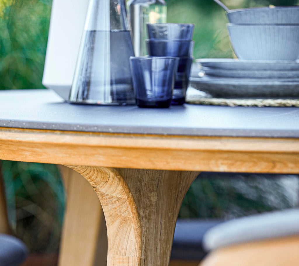 Ein runder Holztisch mit einer glatten Oberfläche, begleitet von Glaswaren und Keramiktellern, die ein stilvolles Essensarrangement schaffen.