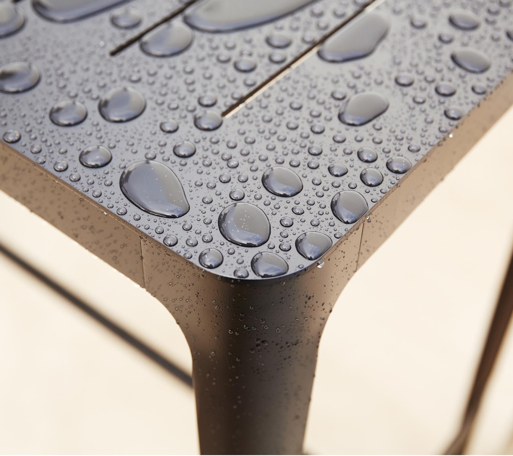 Nahaufnahme einer strukturierten Oberfläche mit Wassertropfen, die das schlanke Design und die Details des Materials hervorheben.
