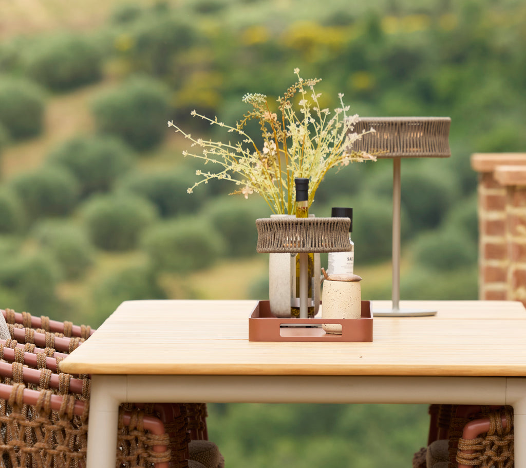 Ein stilvoller Esstisch mit einer Illusionslampe und einer Blumenvase, die ein elegantes Zentrum in einer ruhigen Umgebung schafft.