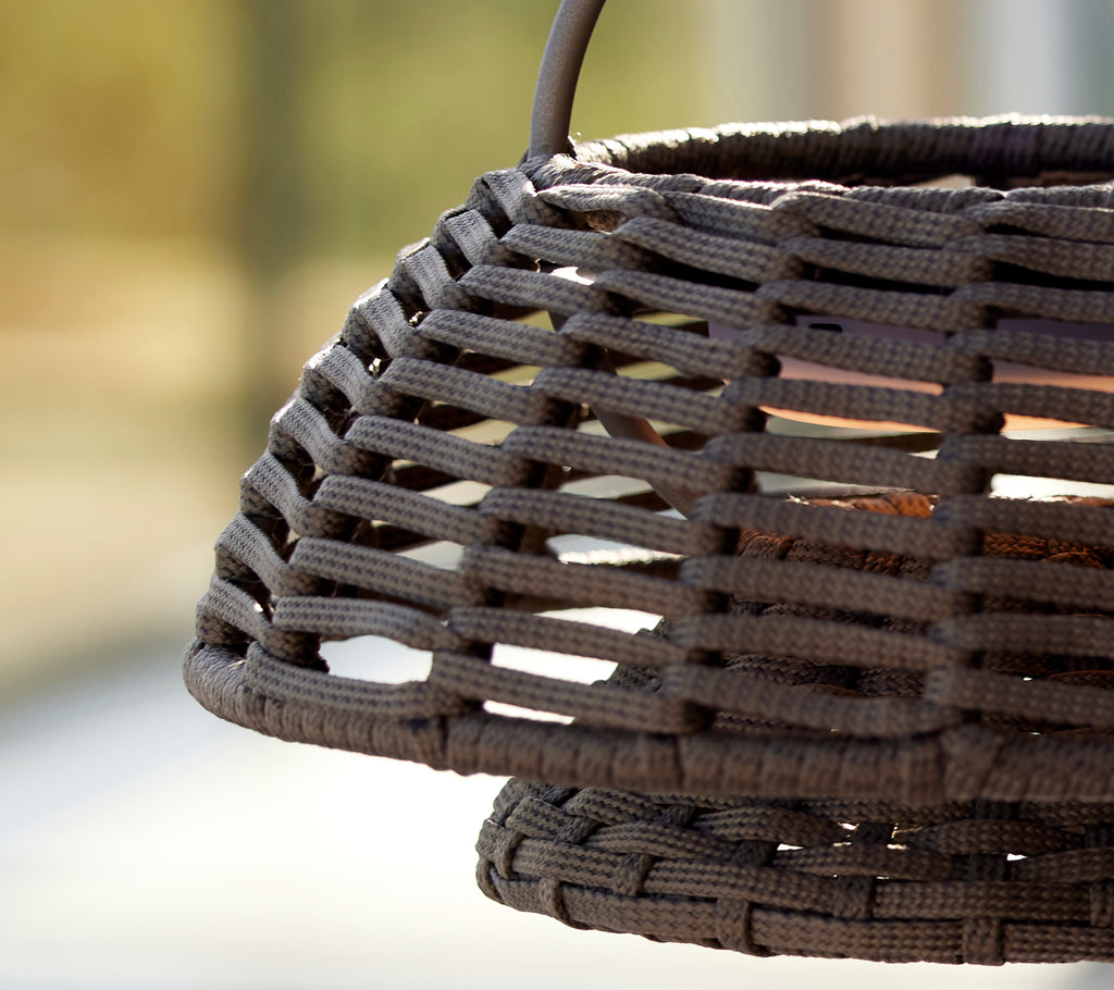 Nahaufnahme einer taupe Illusionslampe mit einem gewebten Design, das komplexe Gittermuster und strukturierte Materialien zeigt.