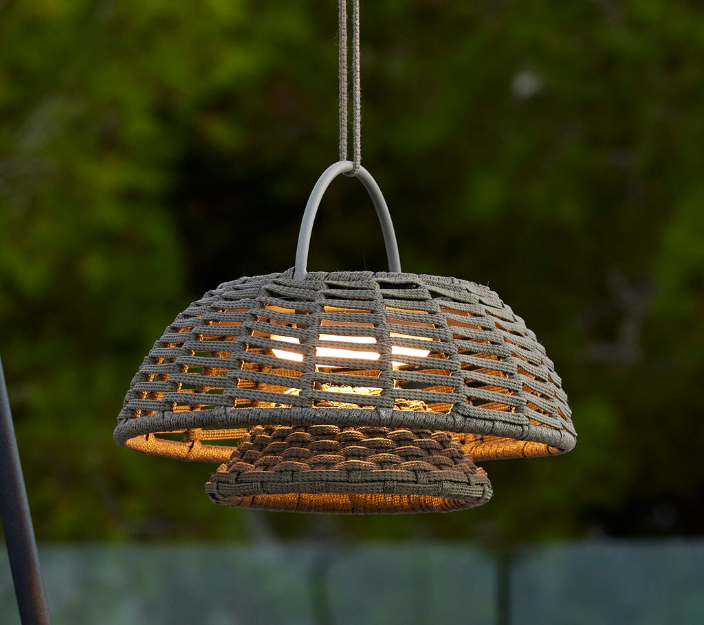 Taupe-Illusionslampe mit einem geflochtenen Design, das eine markante Kuppelform aufweist und warmes Licht von innen ausstrahlt, wodurch eine einladende Atmosphäre entsteht.