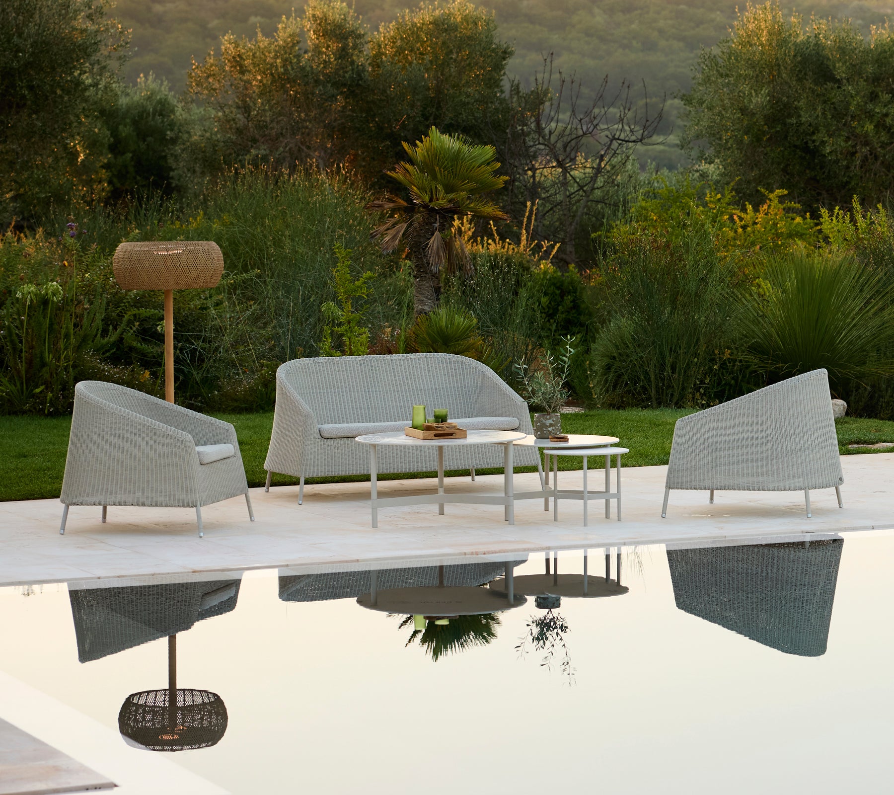 Moderne graues Sofa und Stuhl mit weißem Tisch in einer Outdoor-Lounge-Umgebung.