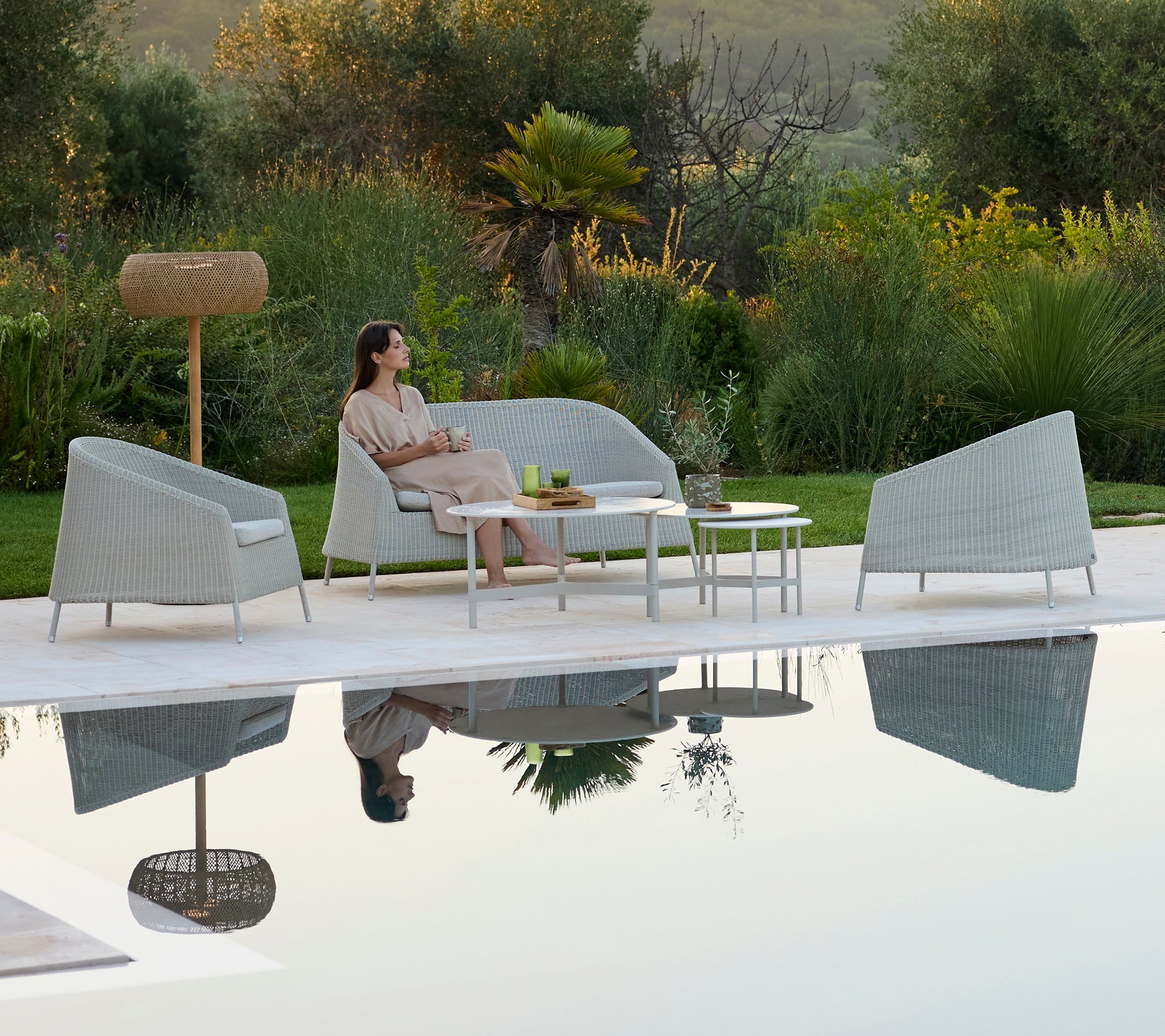 Moderne graues Sofa und Sessel um einen weißen Tisch in einer entspannenden Outdoor-Lounge.
