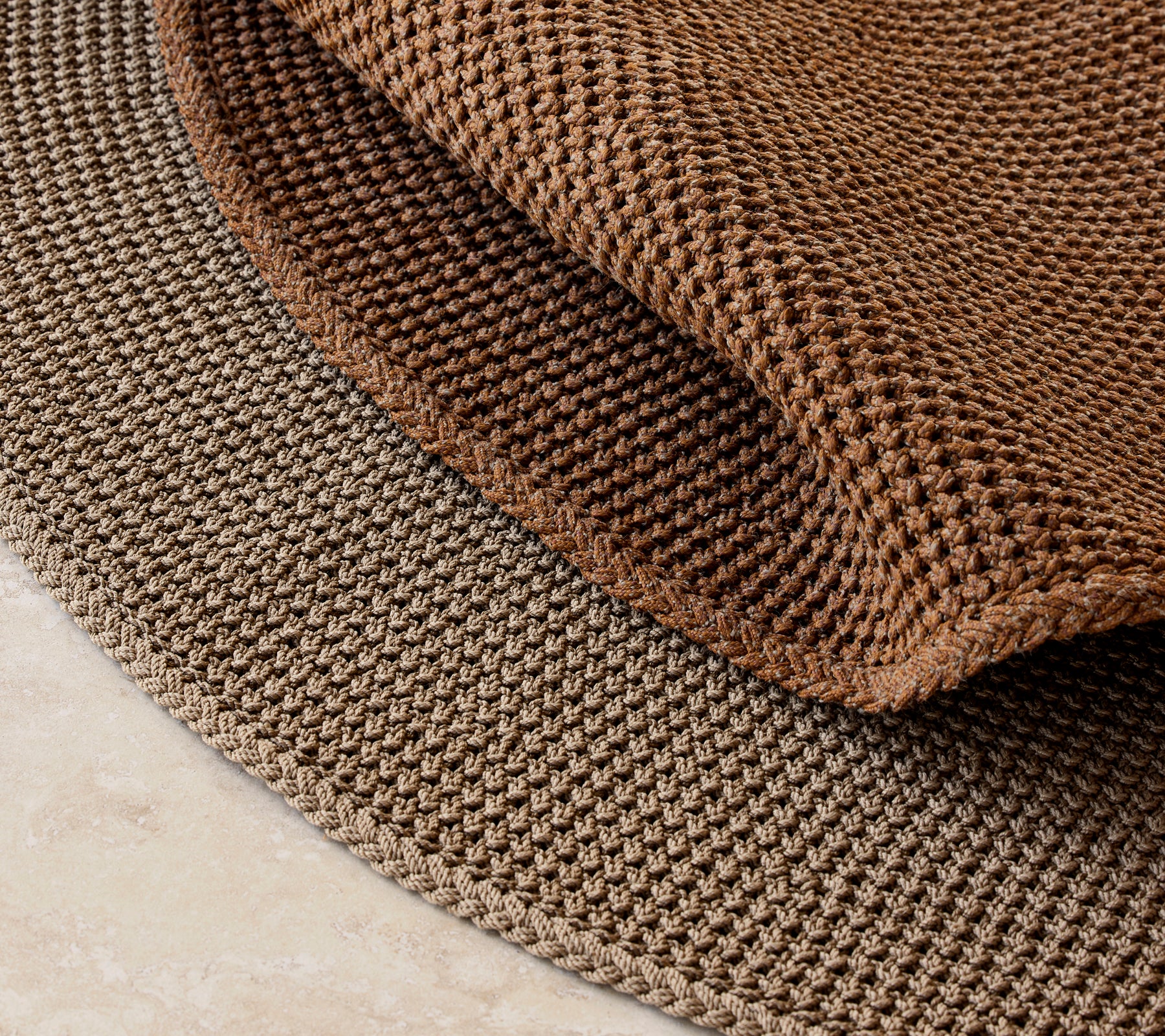 Gestrickter Teppich mit einem Durchmesser von 200 cm, der ein strukturiertes braunes Design und ein geschichtetes Aussehen aufweist.