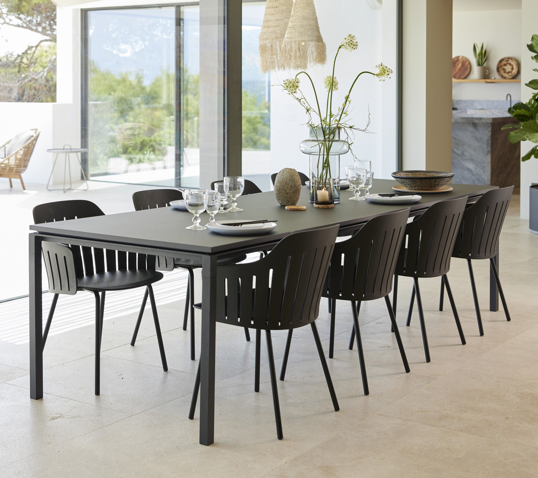 Ein stilvoller Esstisch mit acht schwarzen Stühlen, elegant mit Geschirr und einer Blumenvase als Mittelpunkt dekoriert.
