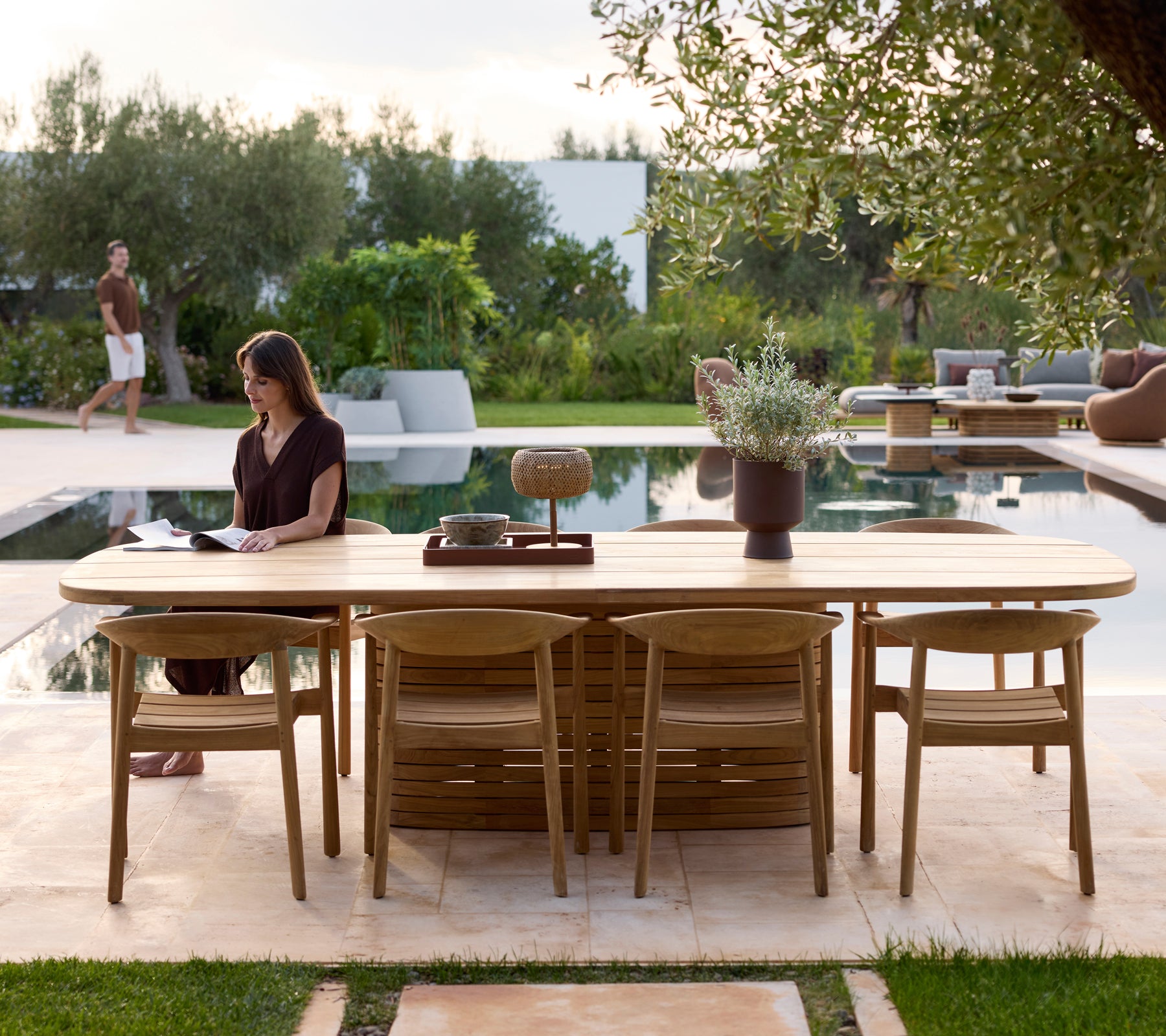 Modernes Gartenmöbel mit Stühlen neben einem Pool, umgeben von Grün.