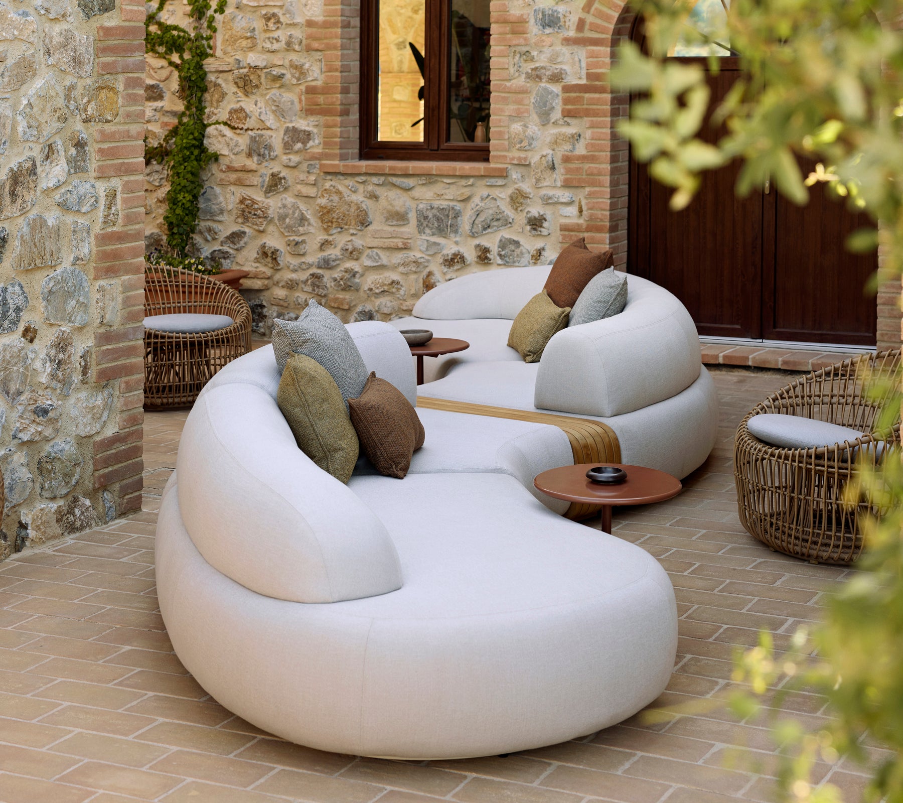 Sanfte Lounge mit einem Nest-Rundstuhl und Tisch Glaze, ergänzt durch dekorative Kissen in einer ruhigen Umgebung.