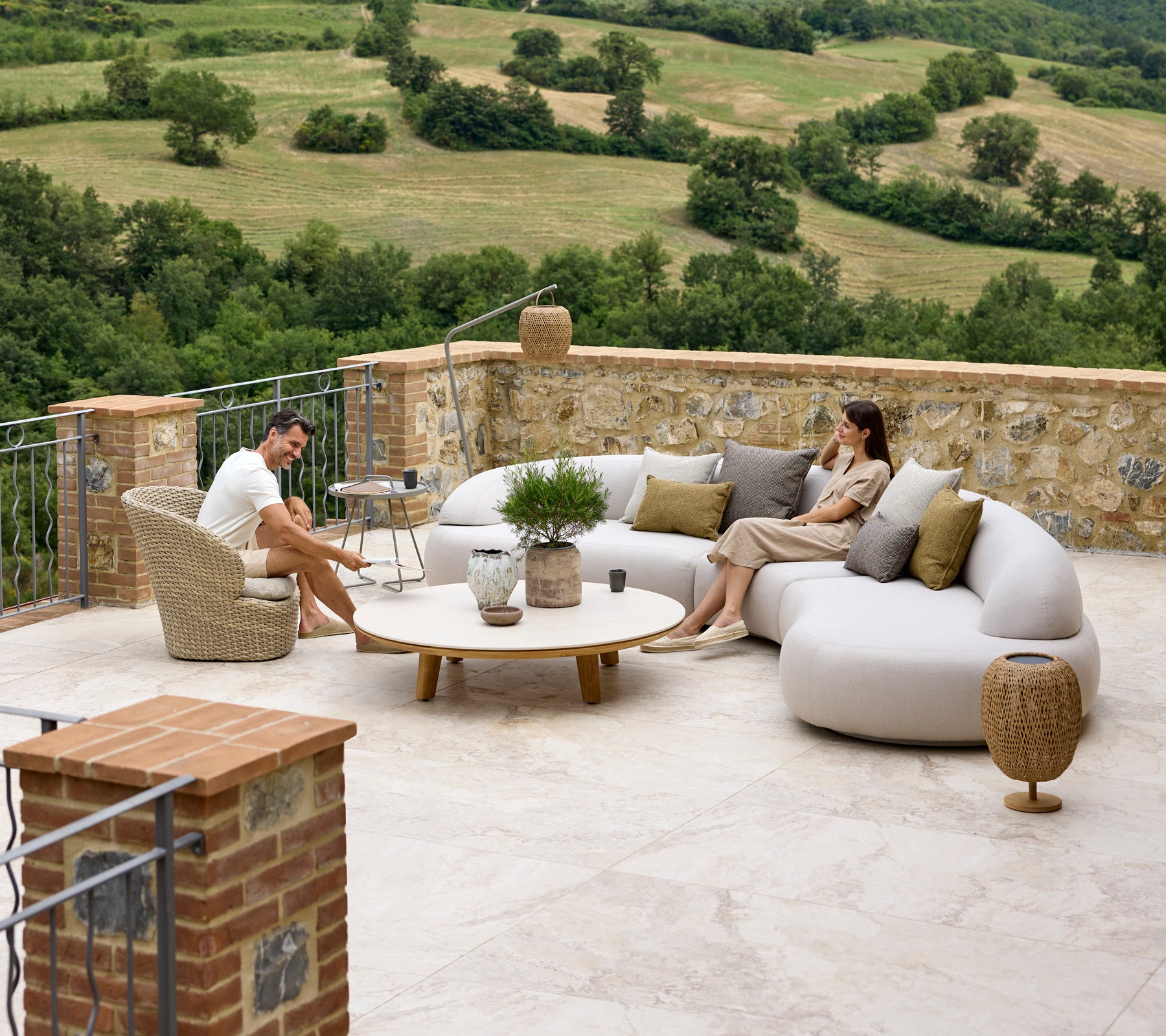 Entspannende Sitzgelegenheit mit einem sanften Lounge-Sofa, Coast-Lounge-Stuhl, Aspect-Couchtisch und Illusion Glow Akzenten vor einer malerischen Kulisse.