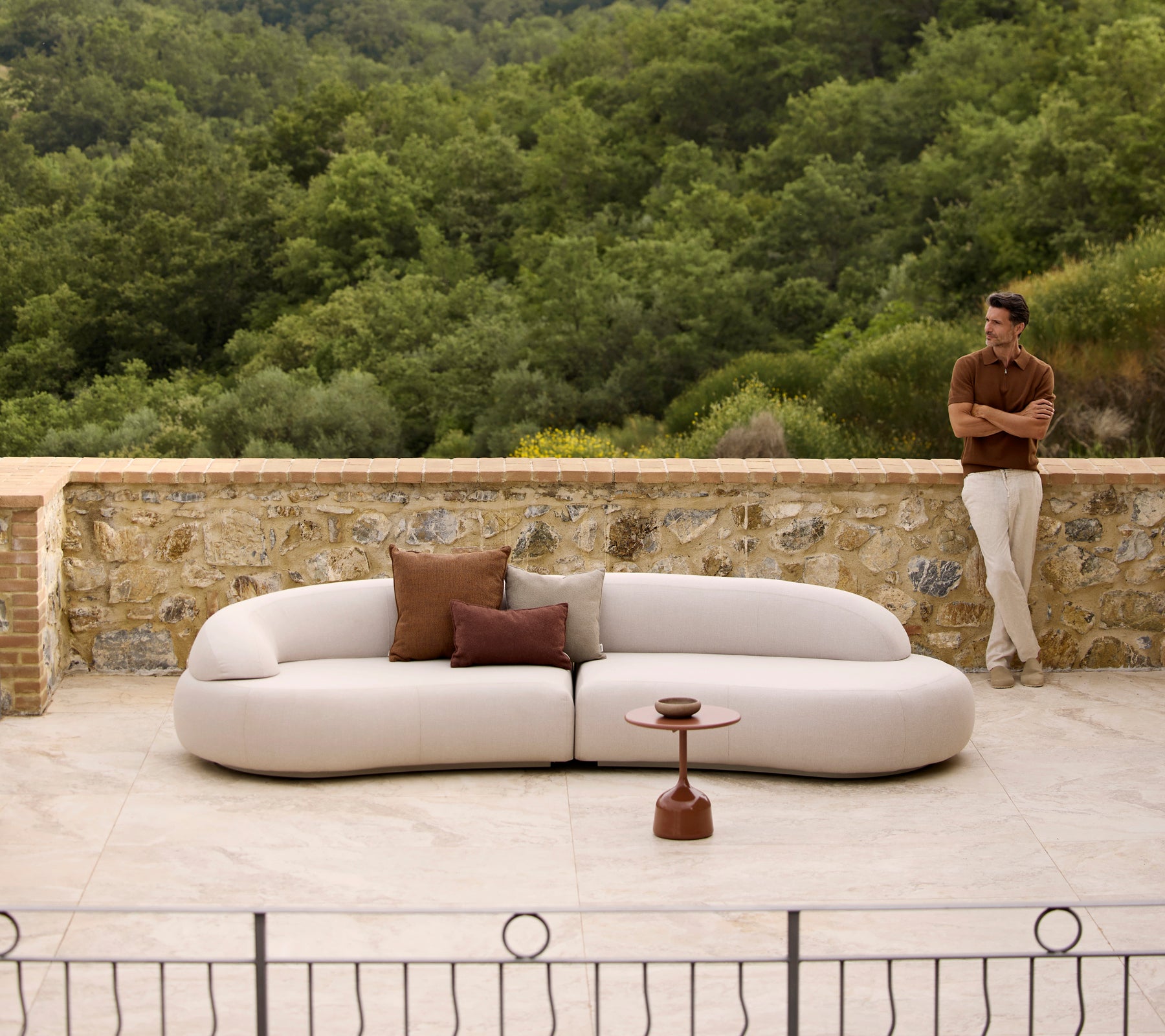 Mellow Lounge-Sofa mit Rise-Kissen und einem Glaze-Couchtisch, vor einem üppigen grünen Hintergrund platziert.