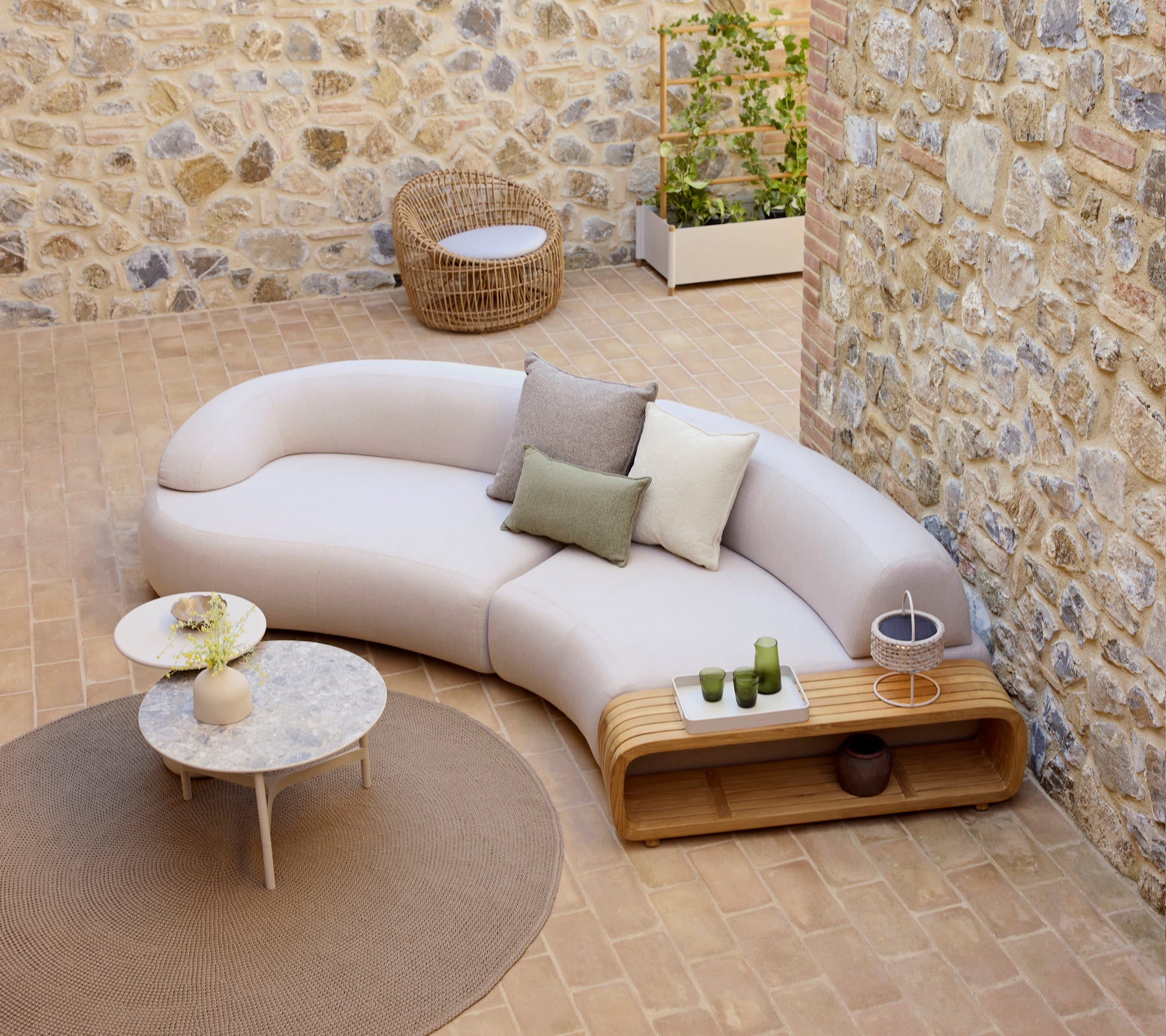 Gekrümmtes, sanftes Sofa mit dekorativen Kissen, ein sanfter Couchtisch und ein runder Neststuhl, auf einem strukturierten Boden.