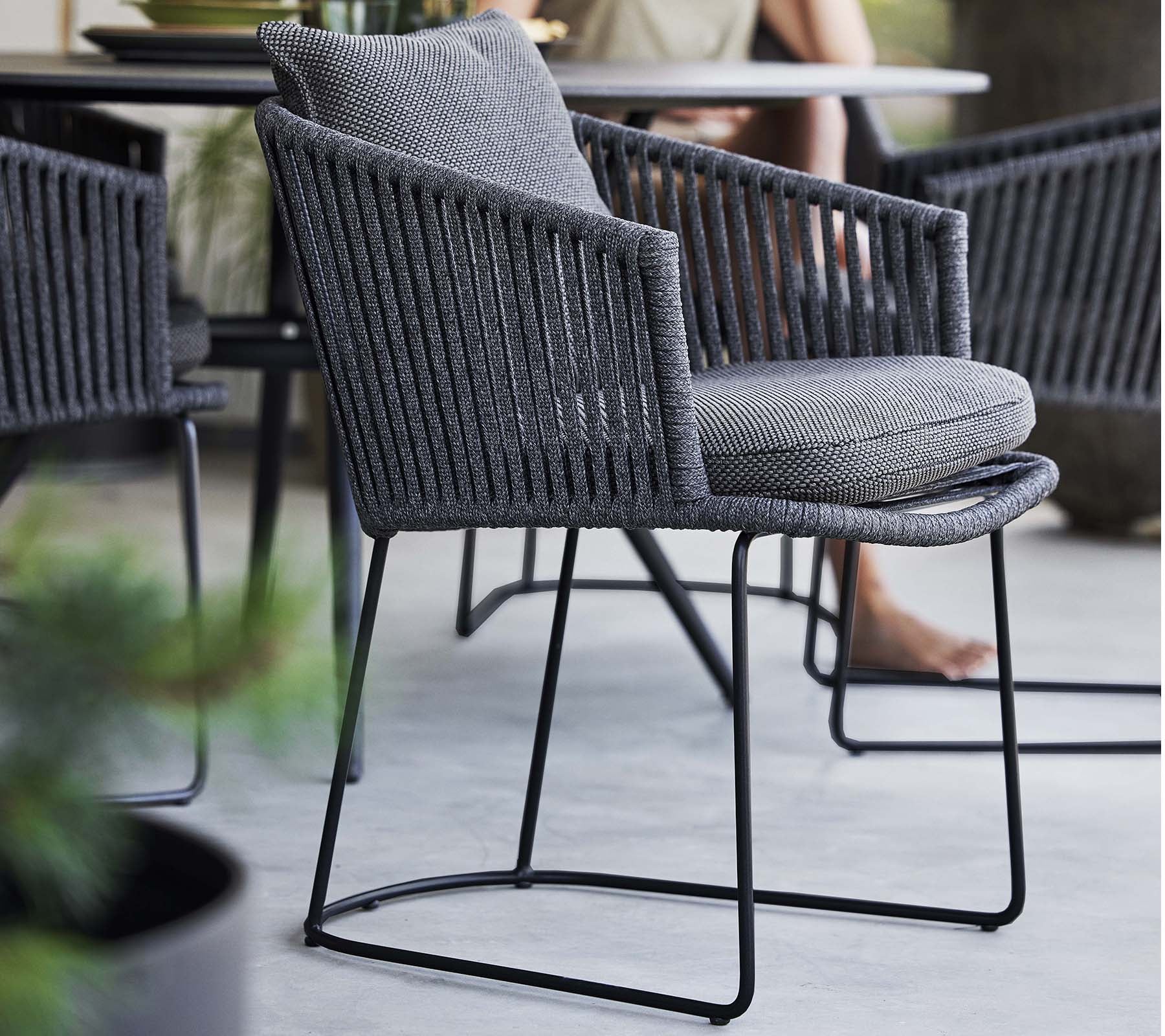 Stilvolle Stuhl mit einem geflochtenen Design und weichem Kissen, unterstützt von einem schlanken Metallrahmen, perfekt für zeitgenössische Räume.