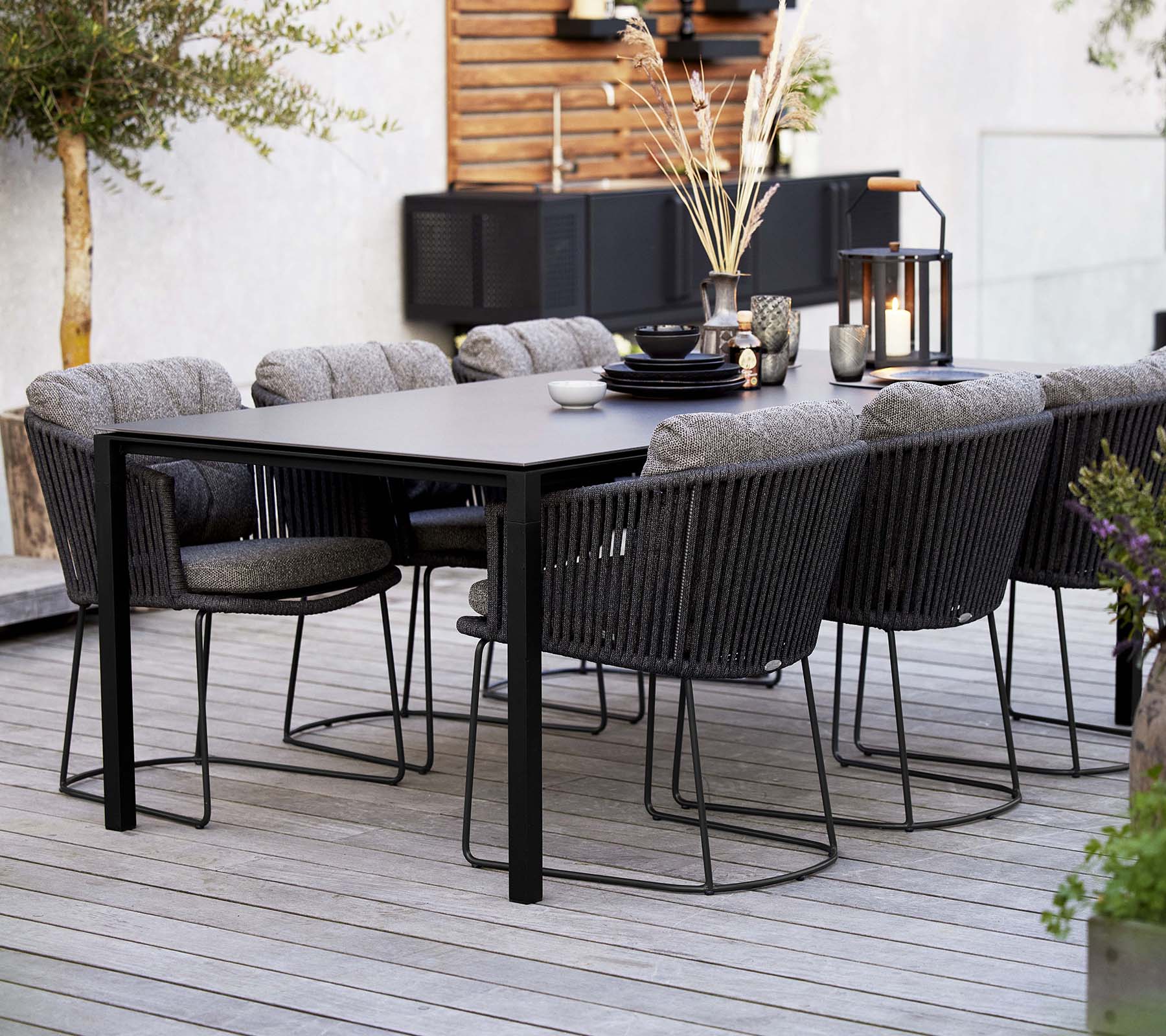 Ein stilvolles Esszimmer-Setup mit einem eleganten Tisch, umgeben von bequemen geflochtenen Stühlen, geschmückt mit dekorativen Elementen und Pflanzen.