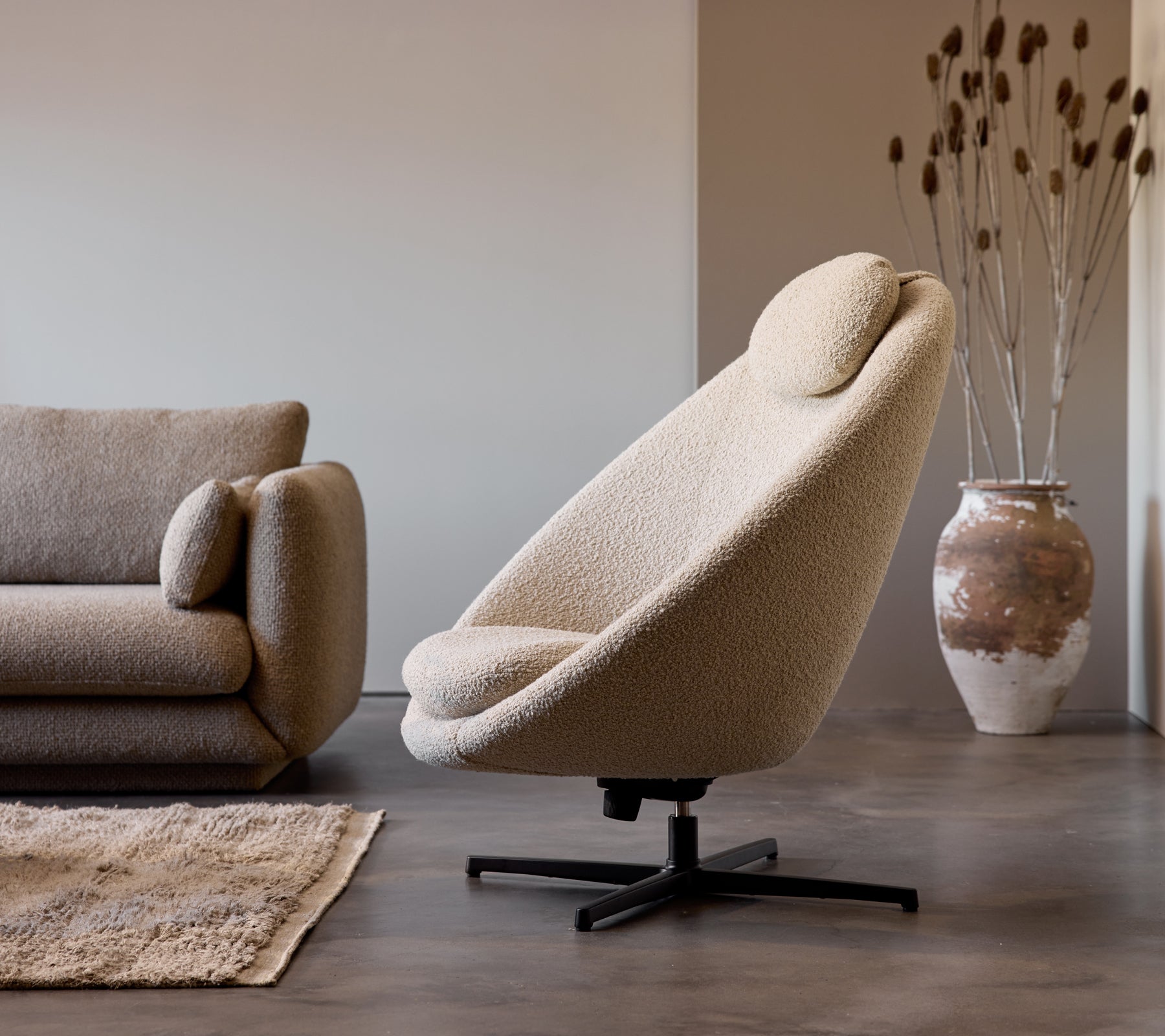 Pace-Stuhl aus taupe Farbmaterial neben einem Bloom 3-Sitzer-Sofa, ergänzt durch eine dekorative Vase und subtile Bodentextur.