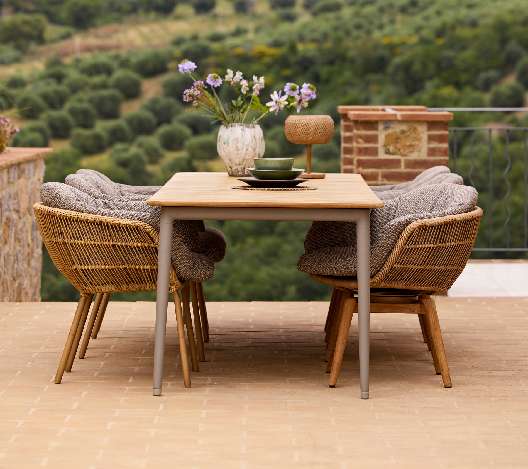 Stylische Essanordnung mit einem Holztisch, zwei Stay-Stühlen mit Aluminiumbeinen und einer Vase mit Blumen und dekorativen Accessoires.