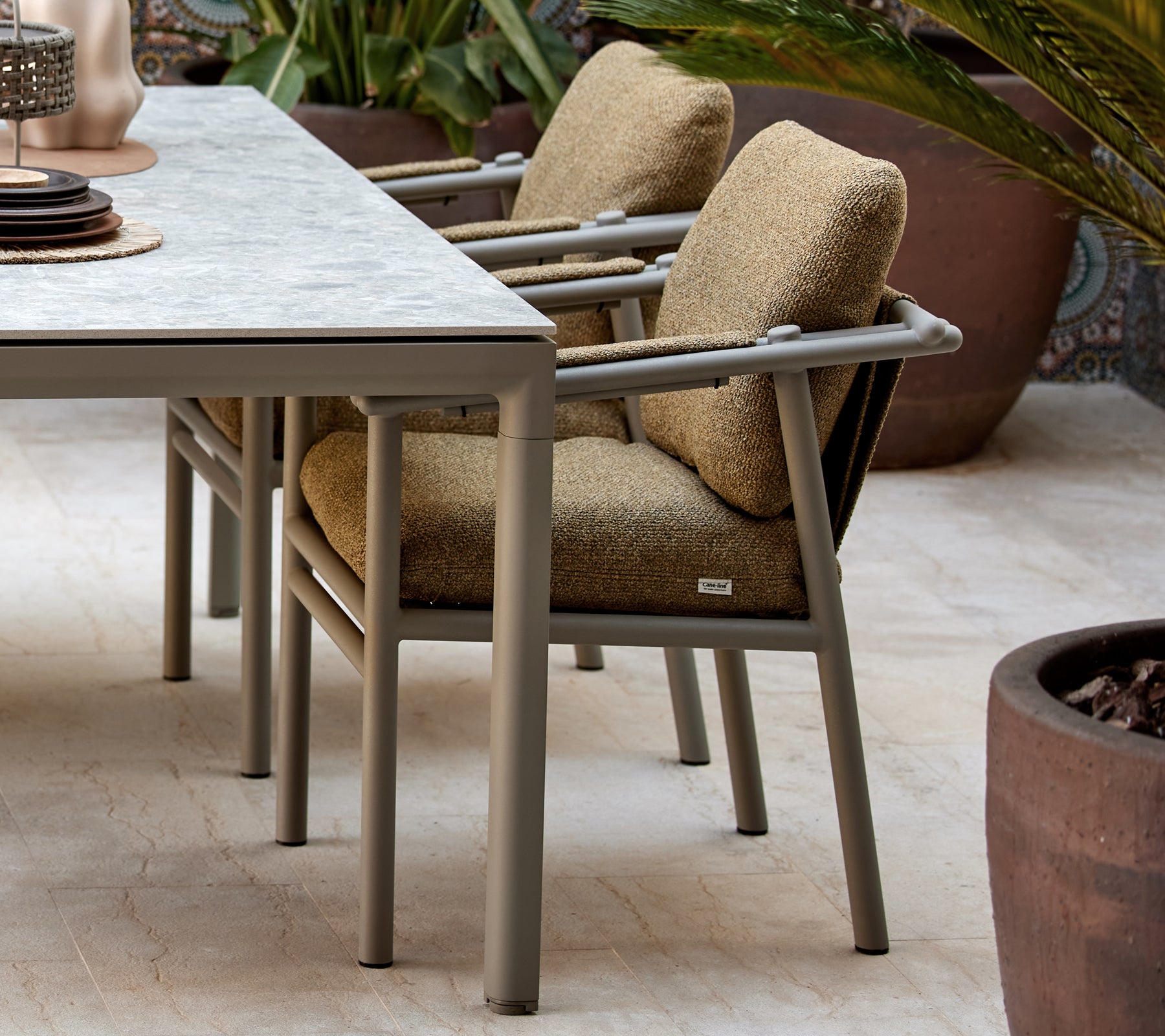 Zwei Essstühle mit weichen Kissen, die ein modernes Design mit stabilen Beinen haben, neben einem Tisch mit dekorativen Gegenständen platziert.