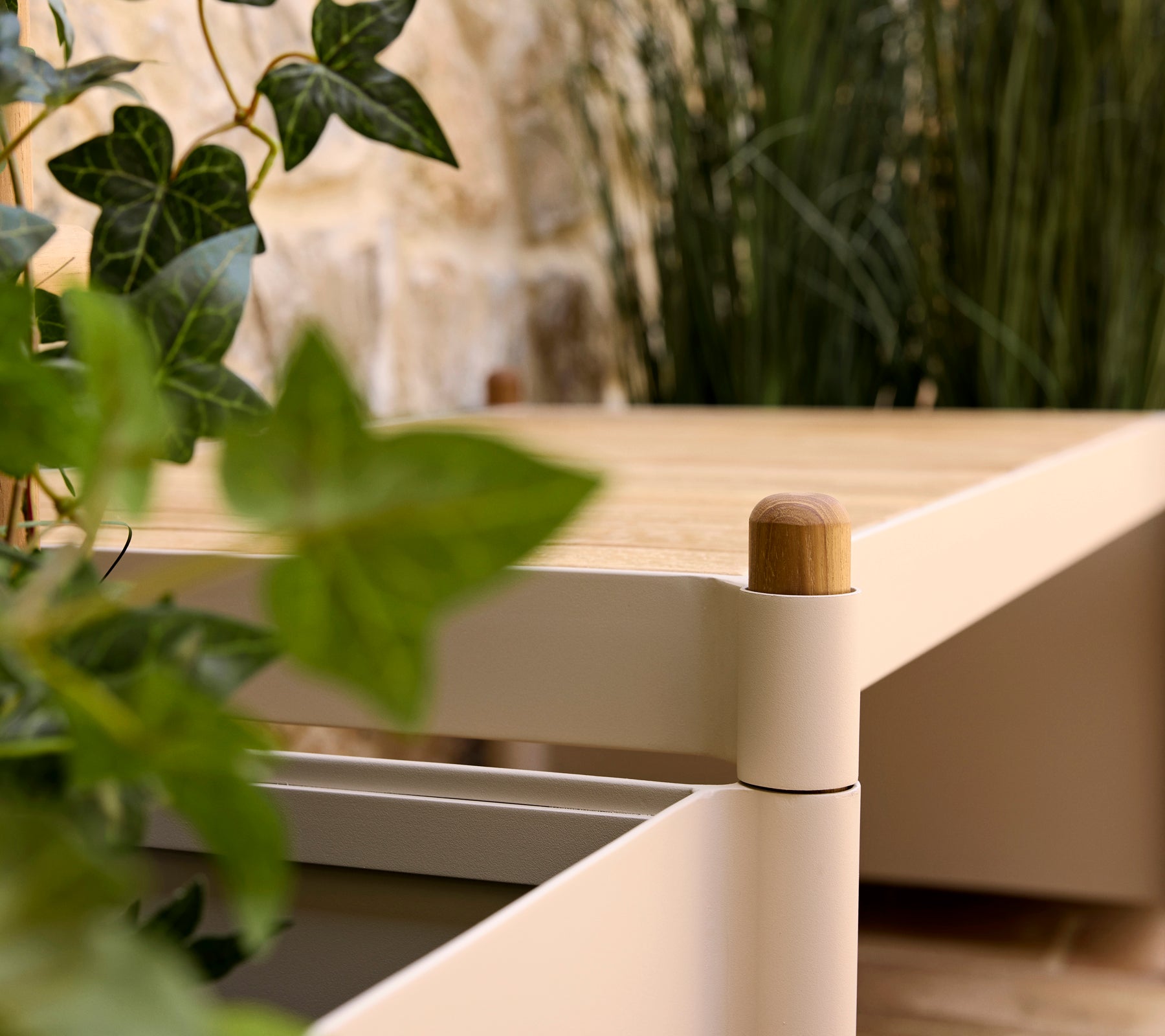 Eine stilvolle Bank mit einer Holztauflage und sanften Kanten, begleitet von Grünpflanzen in einem Blumentopf, die eine ruhige Atmosphäre verbessern.
