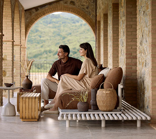 Ein Paar sitzt zusammen auf einem stilvollen Sofa, ergänzt durch einen Couchtisch, dekorative Vasen und eine elegante Hängeleuchte.