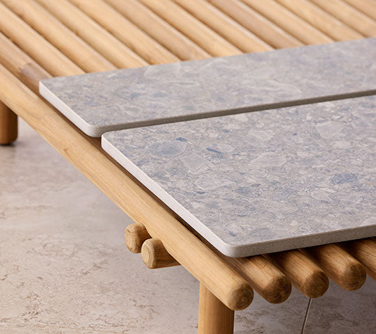 Eine Holzplattform verfügt über zwei Steintischplatten, die ein modernes Design mit naturnahen Elementen für eine stilvolle Präsentation hervorheben.