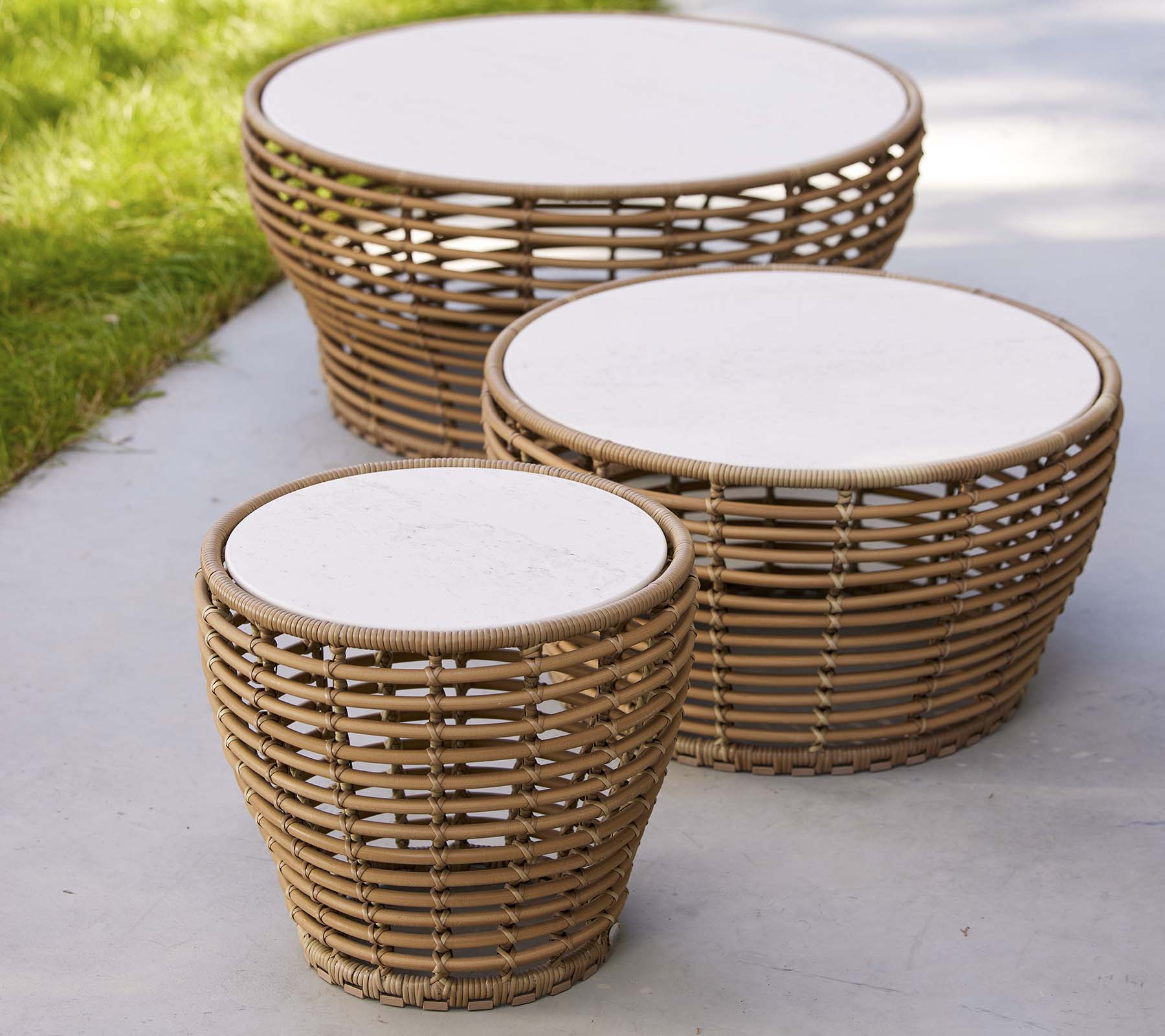 Drei geflochtene Korbkaffetische in unterschiedlichen Größen mit runden weißen Tischplatten und einem natürlichen Design, ideal für einen stilvollen Wohnraum.